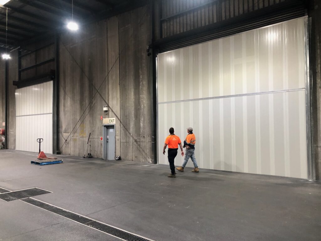 Two workers walking in front of large Sonic System acoustic modular panels