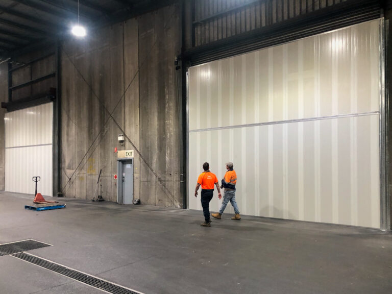 Two workers walking in front of large Sonic System acoustic modular panels