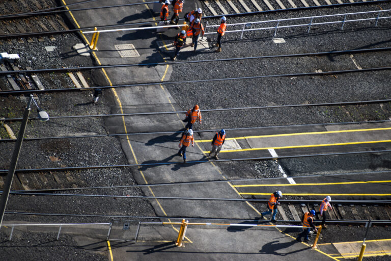 southern Cross station in Melbourne, Victoria, Australia. They are crossing the railway tracks to go to construction site.