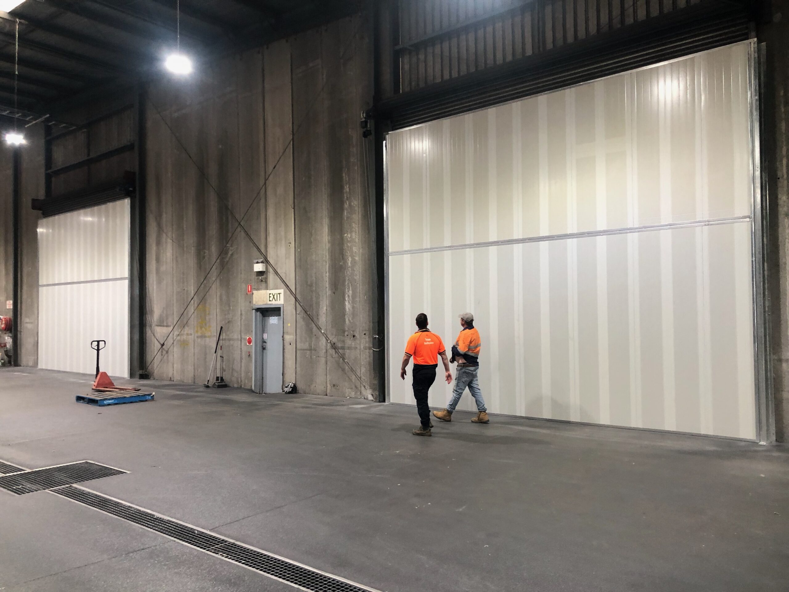 Two workers walking in front of large Sonic System acoustic modular panels