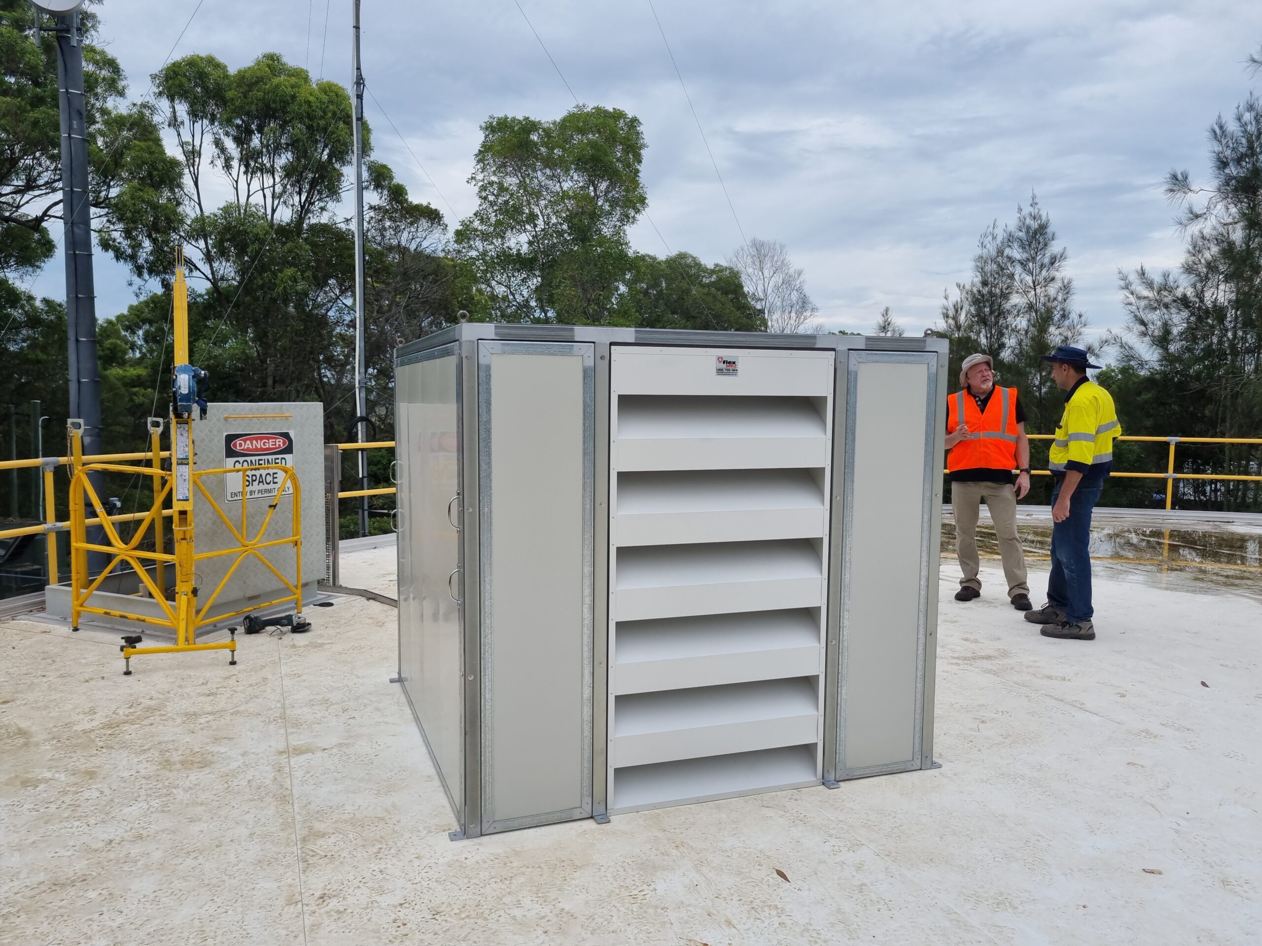 Installers standing beside a recently installed acoustic enclosure