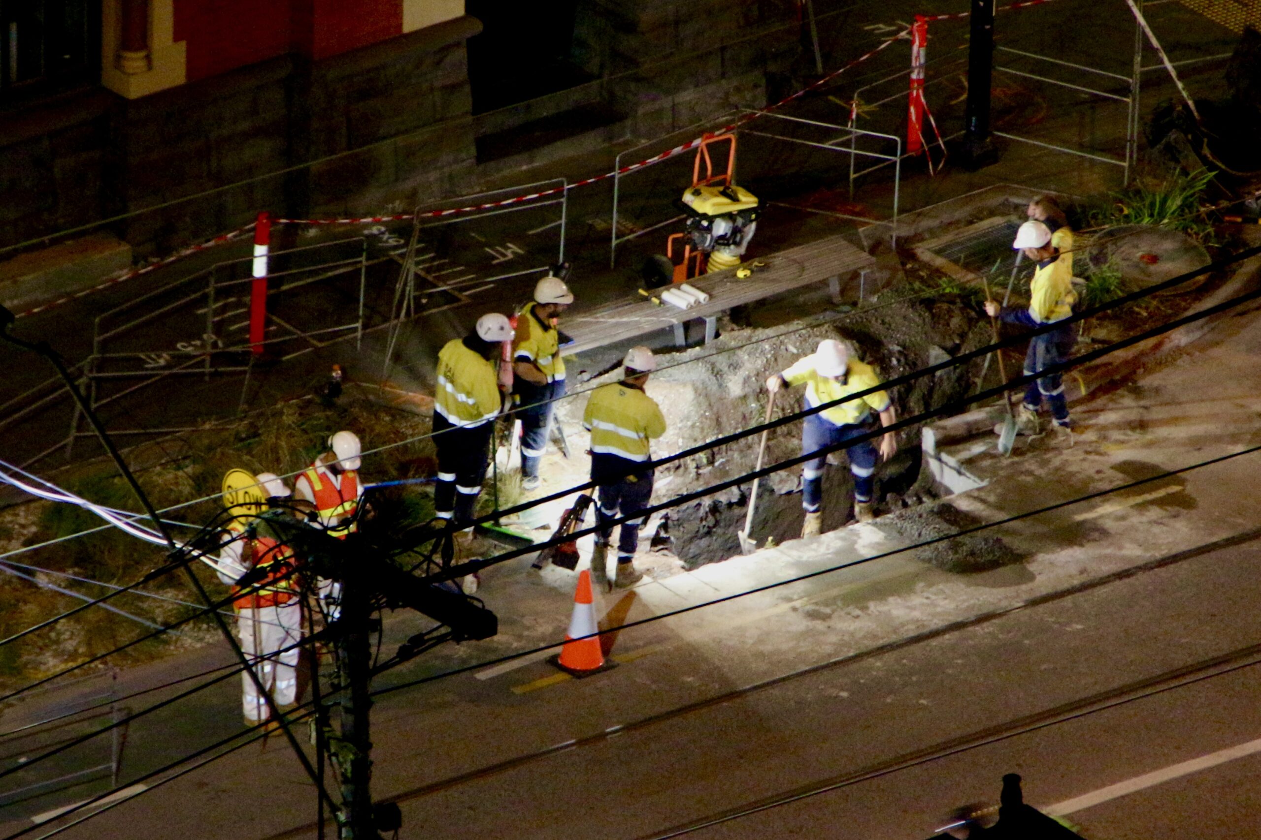 Construction workers at night in a hole with the street closed