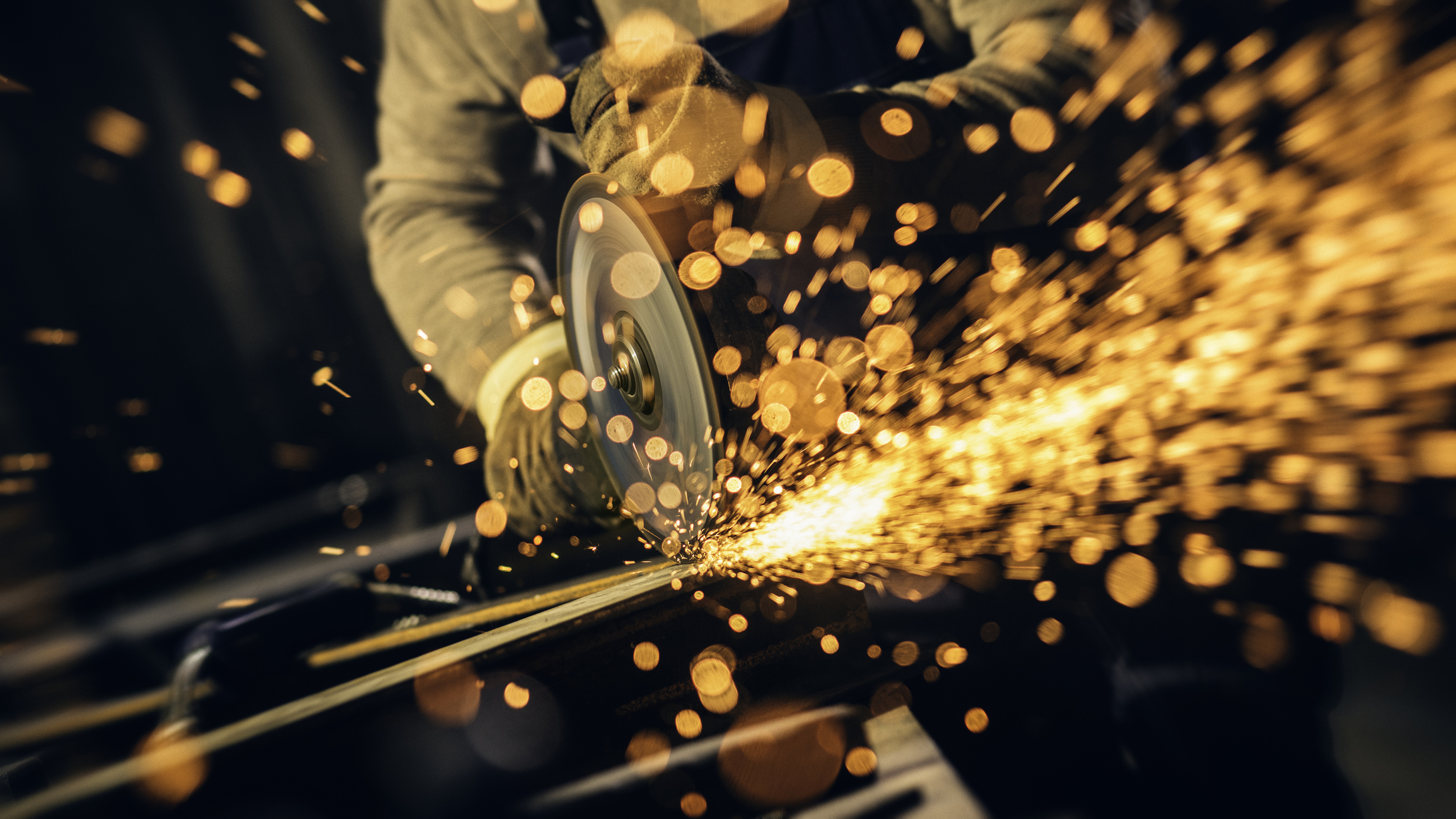 Metal worker cutting a metal objects with circular saw in small workshop.